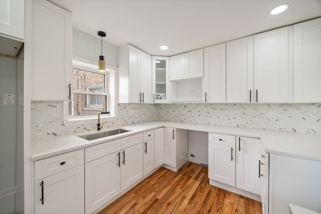8623 S Prairie Ave, Chicago, IL 60619 - kitchen featuring light wood-style flooring, decorative light fixtures, white cabinets, glass insert cabinets, and backsplash