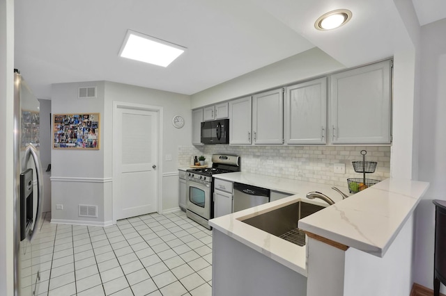 874 Dandridge Ct, Elgin, IL 60120 - kitchen featuring appliances with stainless steel finishes, a peninsula, tasteful backsplash, light stone countertops, and light tile patterned flooring