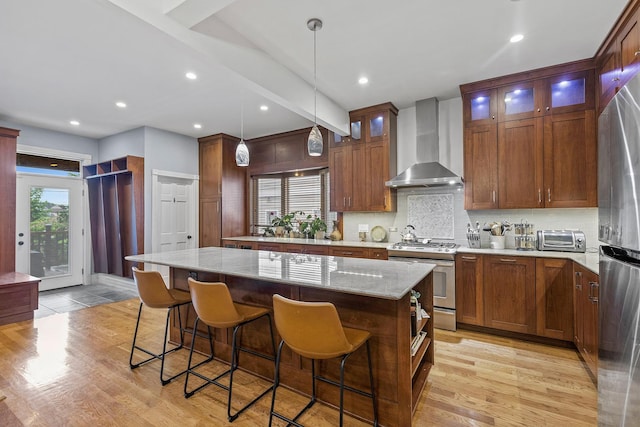 4317 N Kenneth Ave, Chicago, IL 60641 - kitchen with wall chimney range hood, stainless steel appliances, a kitchen island, backsplash, and a breakfast bar area