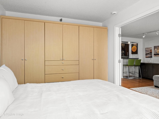 1122 N Clark St Unit 2609, Chicago, IL 60610 - bedroom with a textured ceiling, a closet, wood finished floors, and rail lighting
