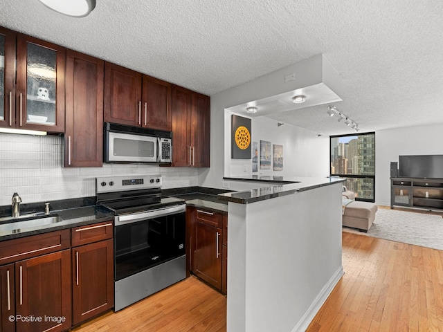1122 N Clark St Unit 2609, Chicago, IL 60610 - kitchen with appliances with stainless steel finishes, a peninsula, open floor plan, light wood-style floors, and a textured ceiling
