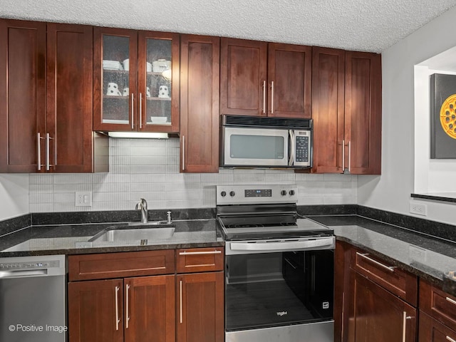 1122 N Clark St Unit 2609, Chicago, IL 60610 - kitchen featuring appliances with stainless steel finishes, dark stone counters, glass insert cabinets, decorative backsplash, and a textured ceiling