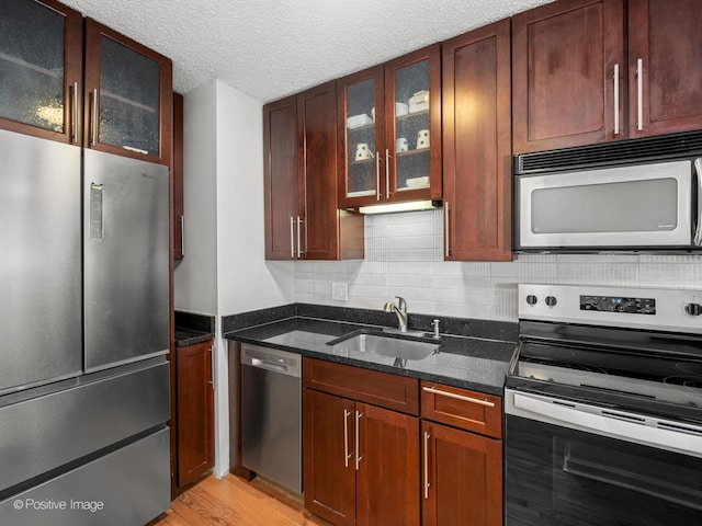 1122 N Clark St Unit 2609, Chicago, IL 60610 - kitchen featuring stainless steel appliances, dark stone counters, light wood-style floors, glass insert cabinets, and a textured ceiling