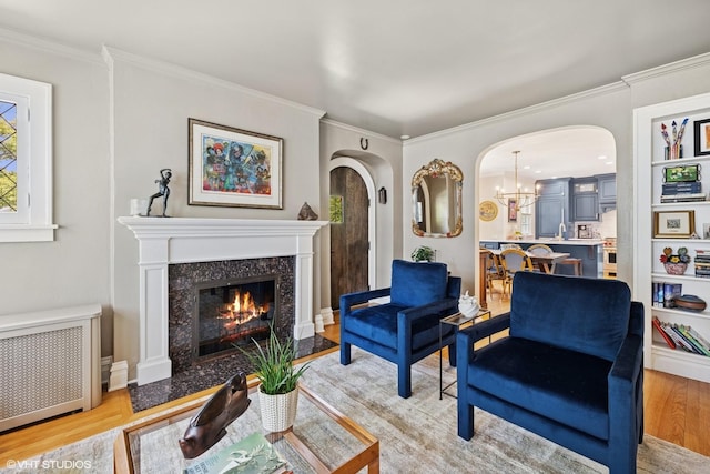 641 Highview Ter, Lake Forest, IL 60045 - living area with arched walkways, radiator, light wood finished floors, ornamental molding, and a fireplace