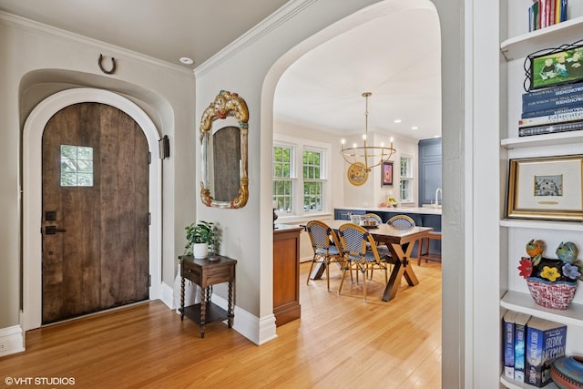 641 Highview Ter, Lake Forest, IL 60045 - entryway featuring arched walkways, a chandelier, light wood-style flooring, and crown molding