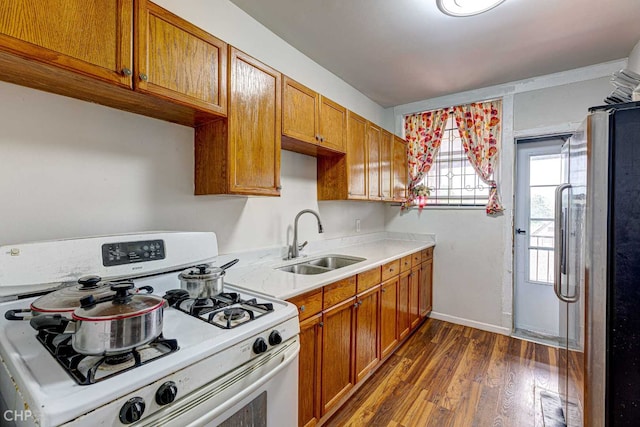 2832 N Mozart St, Chicago, IL 60618 - kitchen with white gas range, freestanding refrigerator, light countertops, dark wood-type flooring, and brown cabinetry