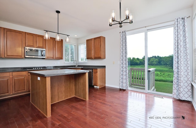 1312 Mulberry Ln, Cary, IL 60013 - kitchen with stainless steel appliances, dark wood-style floors, a chandelier, brown cabinetry, and a kitchen island