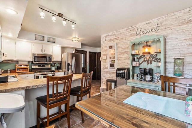 1934 Philip Dr, Dixon, IL 61021 - kitchen with appliances with stainless steel finishes, a kitchen bar, white cabinetry, dark tile patterned flooring, and a peninsula