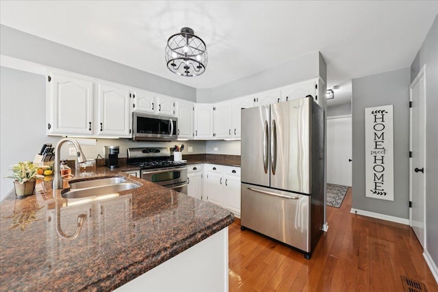 237 Carlisle Ave, Westmont, IL 60559 - kitchen with appliances with stainless steel finishes, white cabinetry, dark stone countertops, wood finished floors, and a chandelier