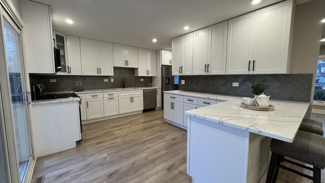 626 E 194th St, Glenwood, IL 60425 - kitchen with stainless steel dishwasher, a peninsula, gas range, light stone counters, and white cabinetry