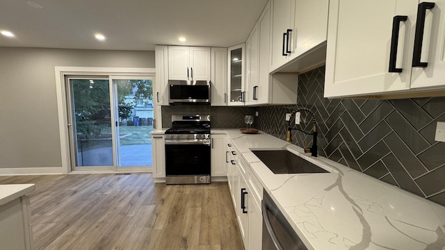 626 E 194th St, Glenwood, IL 60425 - kitchen with stainless steel appliances, light stone countertops, white cabinets, tasteful backsplash, and light wood-style floors