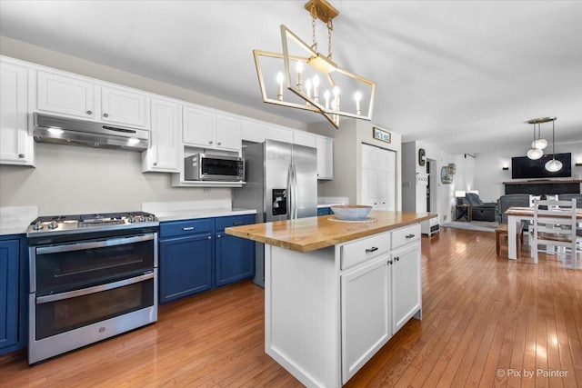 25909 S Woodrush Way, Channahon, IL 60410 - kitchen with blue cabinetry, appliances with stainless steel finishes, under cabinet range hood, wooden counters, and light wood-style floors