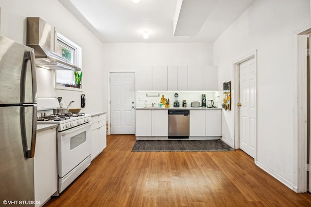 1510 W Cullerton St, Chicago, IL 60608 - kitchen with appliances with stainless steel finishes, wall chimney exhaust hood, white cabinetry, wood finished floors, and modern cabinets