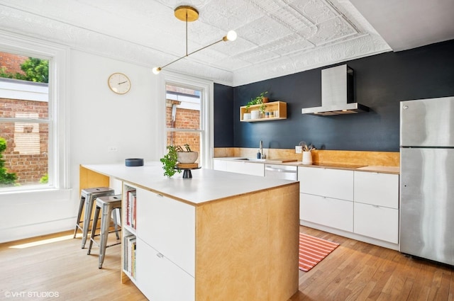 1510 W Cullerton St, Chicago, IL 60608 - kitchen featuring freestanding refrigerator, wall chimney exhaust hood, light wood-style flooring, and white cabinetry