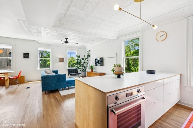 1510 W Cullerton St, Chicago, IL 60608 - kitchen featuring stainless steel oven, light wood finished floors, a ceiling fan, white cabinetry, and light countertops