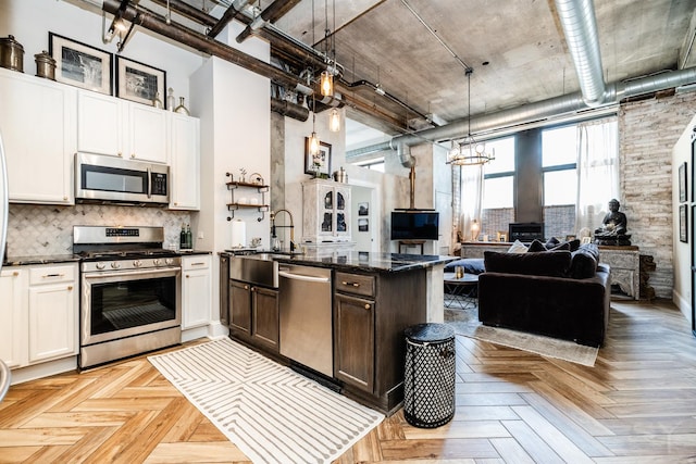 1820 N Spaulding Ave Unit 102, Chicago, IL 60647 - kitchen featuring appliances with stainless steel finishes, open floor plan, tasteful backsplash, a high ceiling, and decorative light fixtures