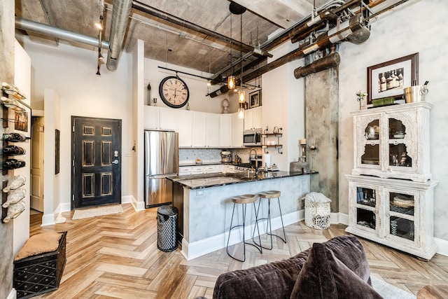 1820 N Spaulding Ave Unit 102, Chicago, IL 60647 - kitchen featuring appliances with stainless steel finishes, a high ceiling, a peninsula, white cabinets, and dark stone counters
