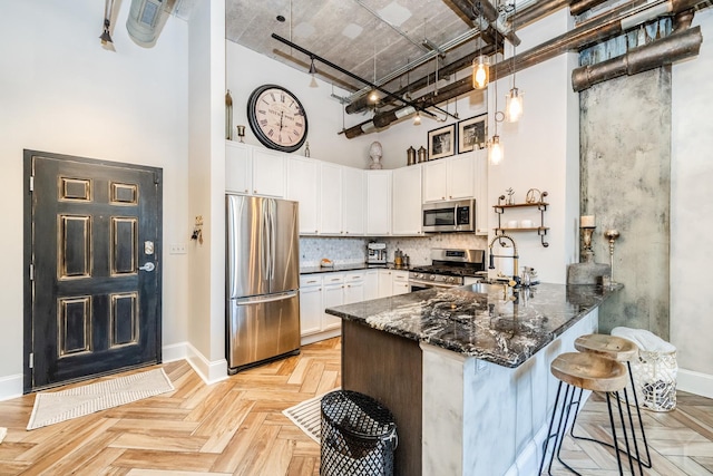 1820 N Spaulding Ave Unit 102, Chicago, IL 60647 - kitchen with stainless steel appliances, a towering ceiling, a peninsula, dark stone countertops, and white cabinets
