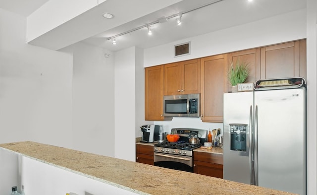 1201 S Prairie Ave Unit 5004, Chicago, IL 60605 - kitchen featuring appliances with stainless steel finishes, brown cabinetry, light stone counters, and track lighting