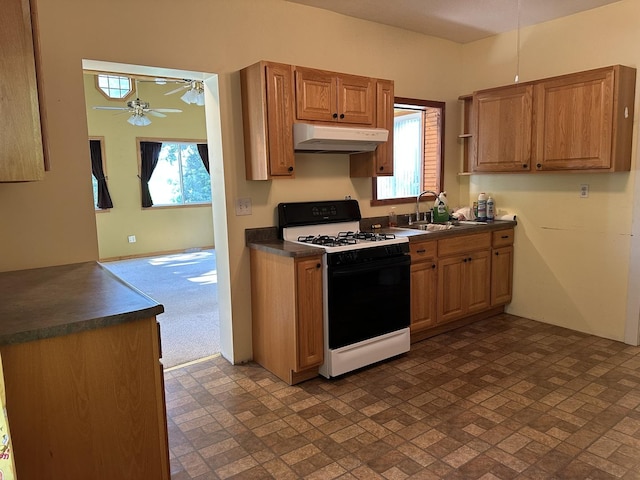 12851 Argo Fay Rd, Thomson, IL 61285 - kitchen featuring range with gas stovetop, under cabinet range hood, dark countertops, a ceiling fan, and healthy amount of natural light