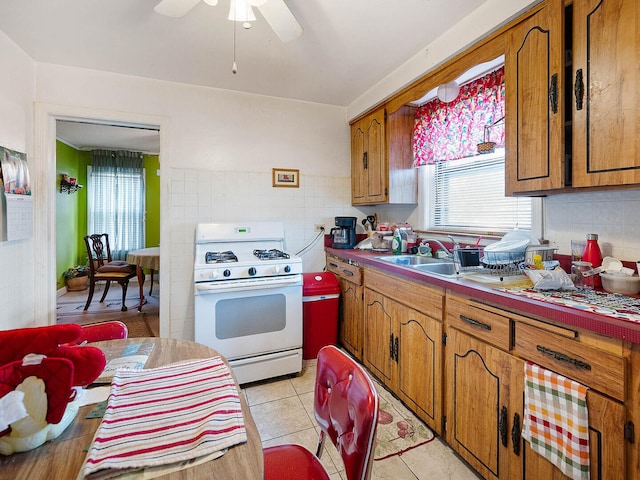 10458 S Forest Ave, Chicago, IL 60628 - kitchen with gas range gas stove, brown cabinets, ceiling fan, tasteful backsplash, and light tile patterned flooring