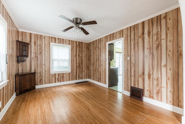 536 Center Ave, Sycamore, IL 60178 - empty room with wood-type flooring, a ceiling fan, ornamental molding, a textured ceiling, and wooden walls
