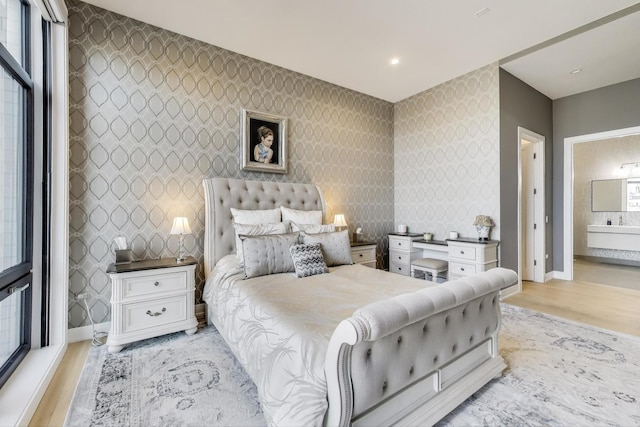 2405 W Iowa St Unit 405, Chicago, IL 60622 - bedroom with light wood-type flooring, an accent wall, ensuite bath, wallpapered walls, and multiple windows