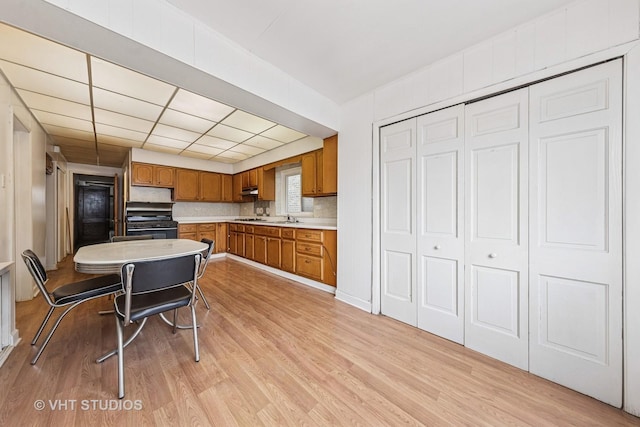 925 W 31st St, Chicago, IL 60608 - kitchen with brown cabinetry, gas stove, light wood-style flooring, light countertops, and a paneled ceiling
