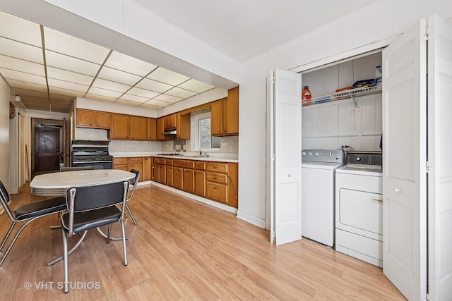 925 W 31st St, Chicago, IL 60608 - kitchen with brown cabinets, black range oven, light countertops, light wood-style floors, and washer and clothes dryer