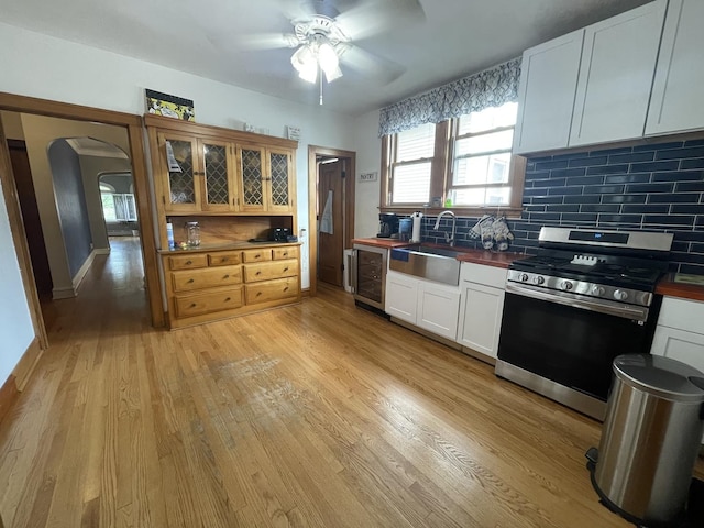 2918 N Normandy Ave, Chicago, IL 60634 - kitchen featuring stainless steel gas stove, light wood-type flooring, ceiling fan, and tasteful backsplash
