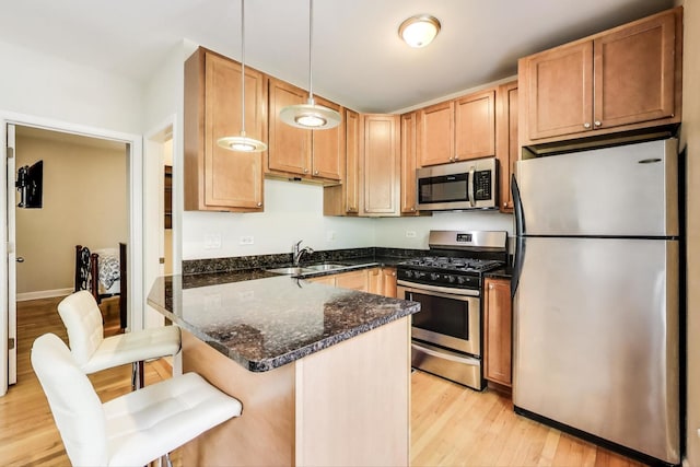 3005 N Clifton Ave Unit 201, Chicago, IL 60657 - kitchen with appliances with stainless steel finishes, light wood-style floors, dark stone countertops, pendant lighting, and a breakfast bar area