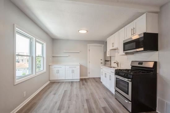 3131 N Odell Ave, Chicago, IL 60707 - kitchen with stainless steel appliances, white cabinetry, light wood-style floors, and light countertops