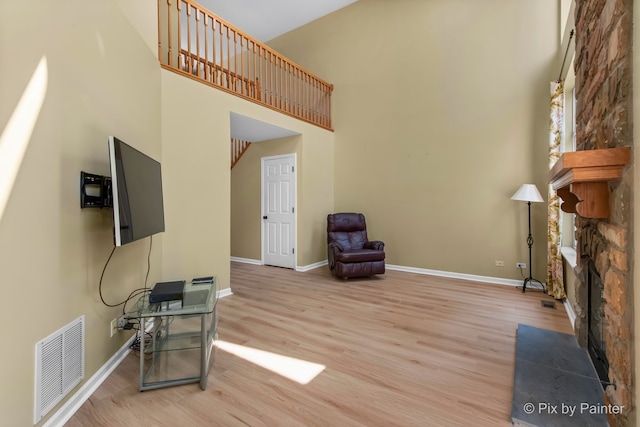 1521 E Baronet Ln, Palatine, IL 60074 - unfurnished living room featuring light wood-style flooring, a towering ceiling, and a stone fireplace