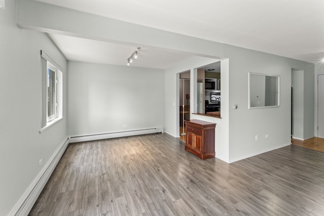 2319 E Olive St Unit 1D, Arlington Heights, IL 60004 - unfurnished living room with a baseboard heating unit, baseboard heating, wood finished floors, and rail lighting