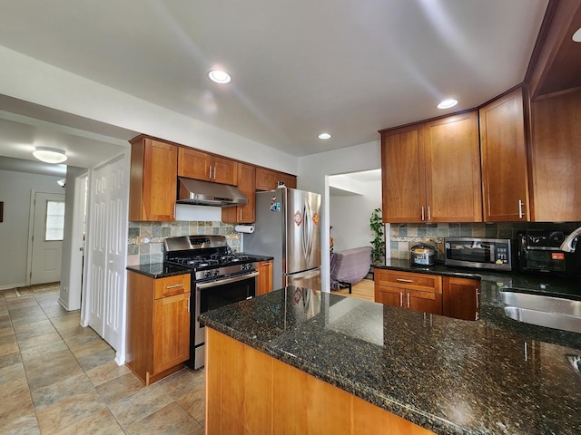 72 Wilton Ln, Mundelein, IL 60060 - kitchen with appliances with stainless steel finishes, under cabinet range hood, tasteful backsplash, dark stone countertops, and recessed lighting