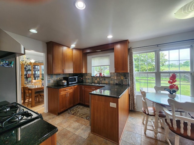 72 Wilton Ln, Mundelein, IL 60060 - kitchen featuring black range with gas cooktop, decorative backsplash, dark stone countertops, stainless steel microwave, and a peninsula