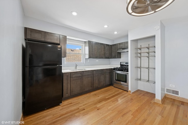 3012 N Nottingham Ave, Chicago, IL 60634 - kitchen with freestanding refrigerator, stainless steel range with gas cooktop, light countertops, dark brown cabinetry, and light wood-type flooring