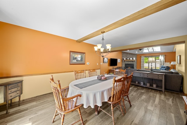 541 Donald St, Hinckley, IL 60520 - dining room featuring a brick fireplace, beam ceiling, wood finished floors, a ceiling fan, and a chandelier