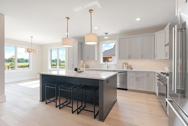 11049 Lizmore Ln Unit 40B, Orland Park, IL 60467 - kitchen with appliances with stainless steel finishes, decorative backsplash, light wood-style flooring, a center island, and light countertops