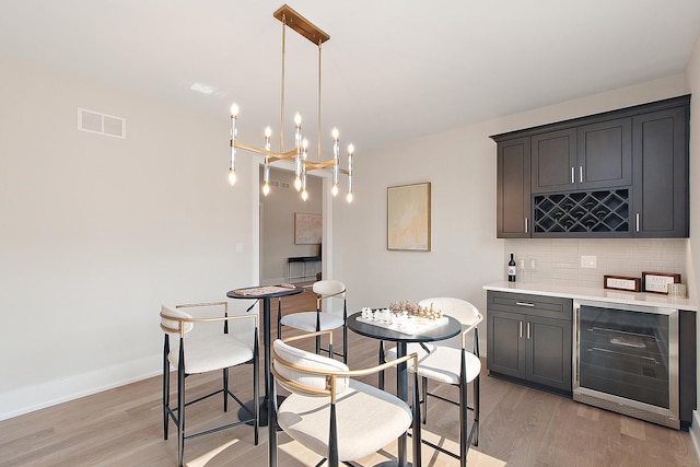11049 Lizmore Ln Unit 40B, Orland Park, IL 60467 - dining space featuring beverage cooler, light wood-style flooring, a bar, and a chandelier