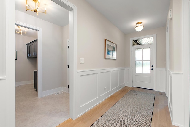 11049 Lizmore Ln Unit 40B, Orland Park, IL 60467 - doorway featuring a chandelier, wainscoting, and light wood-type flooring