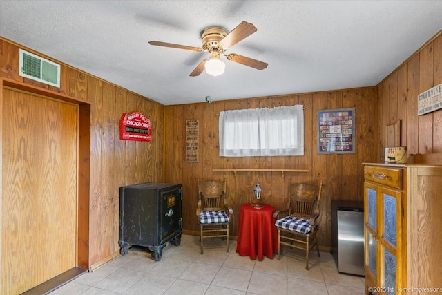 8011 Lawler Ave, Burbank, IL 60459 - living area with a wood stove, wood walls, a ceiling fan, tile patterned floors, and a textured ceiling