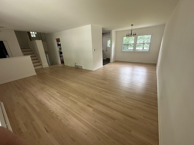 1028 Castlewood Ln, Deerfield, IL 60015 - unfurnished living room with a chandelier, stairs, light wood finished floors, and a baseboard radiator