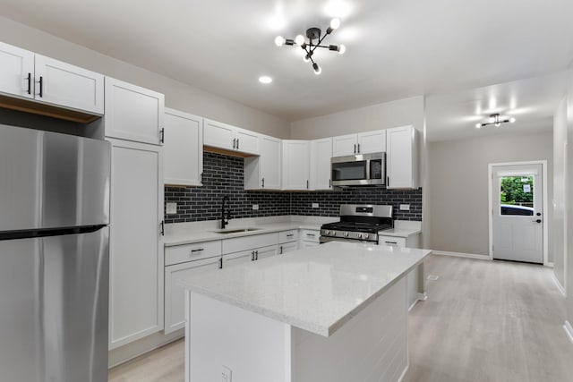 444 Villa St, Elgin, IL 60120 - kitchen with appliances with stainless steel finishes, light wood-type flooring, tasteful backsplash, a kitchen island, and white cabinets