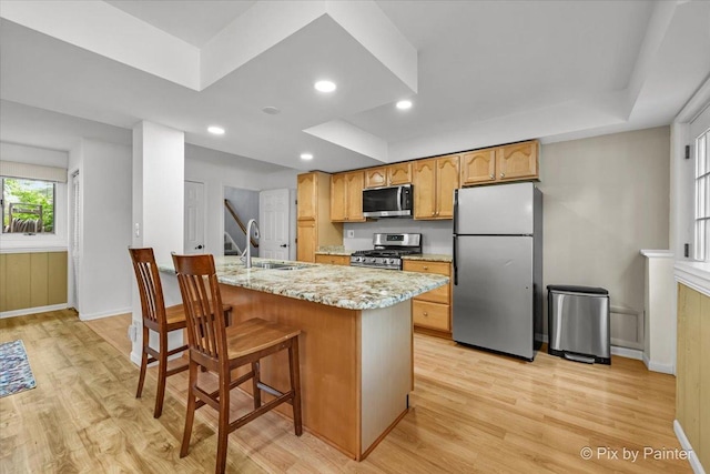 404 Kensington Dr, Mchenry, IL 60050 - kitchen with stainless steel appliances, a tray ceiling, light wood finished floors, light stone countertops, and a breakfast bar