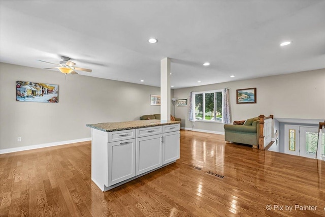 404 Kensington Dr, Mchenry, IL 60050 - kitchen with open floor plan, light wood-style floors, ceiling fan, stone counters, and white cabinets