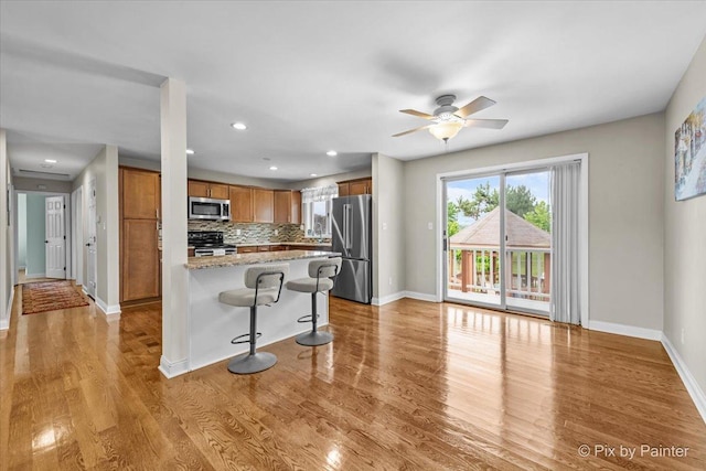 404 Kensington Dr, Mchenry, IL 60050 - kitchen with stainless steel appliances, a kitchen breakfast bar, decorative backsplash, wood finished floors, and ceiling fan