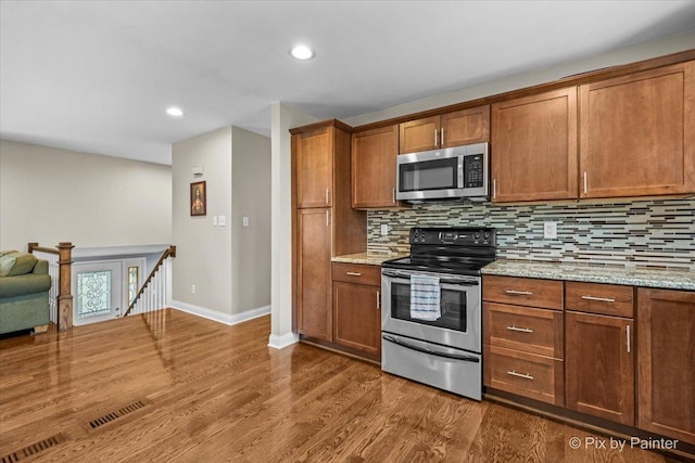 404 Kensington Dr, Mchenry, IL 60050 - kitchen featuring appliances with stainless steel finishes, backsplash, dark wood-type flooring, brown cabinets, and light stone counters