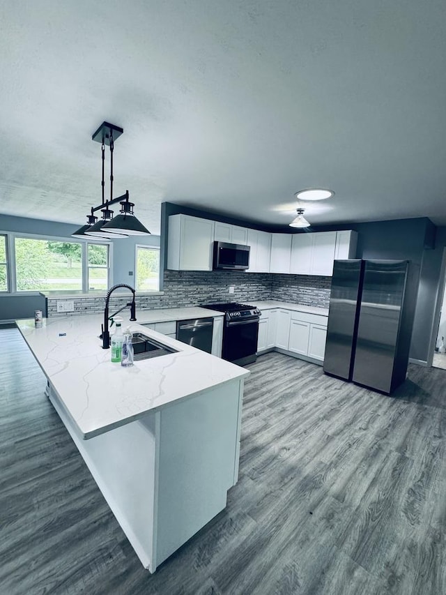 5907 Kirkwood Dr, Rockford, IL 61109 - kitchen with stainless steel appliances, a peninsula, light stone countertops, white cabinetry, and decorative backsplash