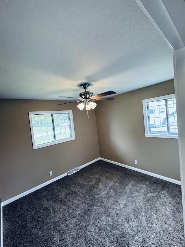 5907 Kirkwood Dr, Rockford, IL 61109 - unfurnished room with plenty of natural light, dark colored carpet, a ceiling fan, and a textured ceiling